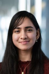 Photo of Aleena Malik, BBA student at Michigan Ross with long straight dark hair wearing a dark red sweater with a gold necklace and smiling 