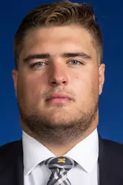 Man with short hair wearing a suit and Michigan tie