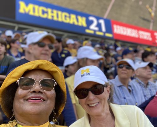 B.R. Proctor and a friend at the Homecoming football game posing in the stands near the score, which is Michigan 21 and Arkansas State 3.