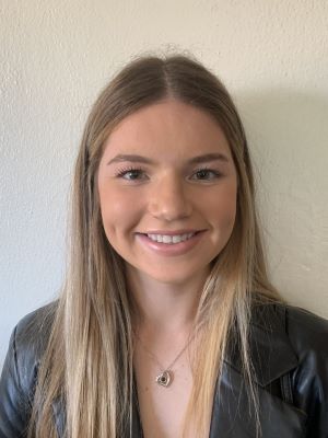 Riley Balconi smiles with a white background behind her.