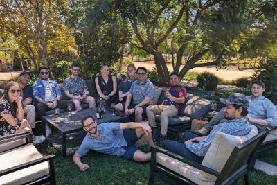 Photo of a group of OMBA students sitting in the grass outside a winery in Chile. 