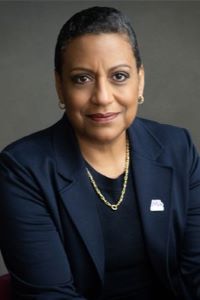 Photo of Stacy Stewart with short dark hair wearing a navy blue suit jacket