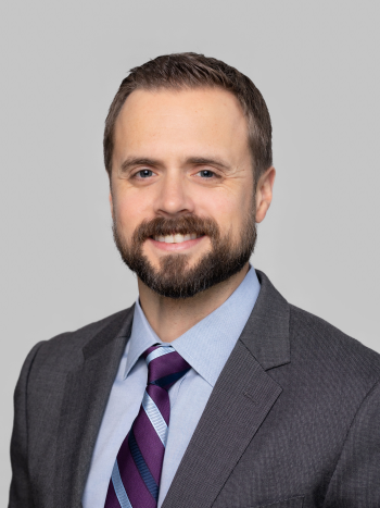 Jarrod Wood smiling with a grey background behind him.