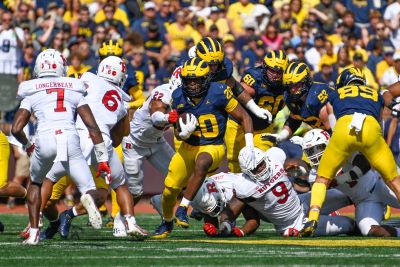 Photo of Kalel Mullings wearing a University of Michigan uniform running with the football on the field