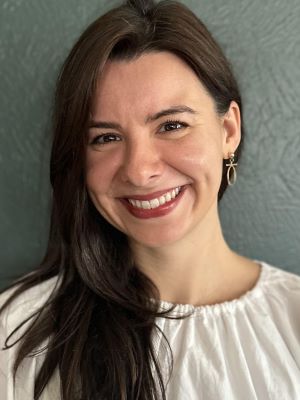 Woman with long dark hair wearing a white shirt and smiling