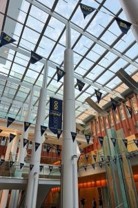 Photo of interior of Ross School of Business building with a glass ceiling and blue banners celebrating the 100-year anniversary of the school. 