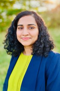 Photo of Suba Ramachandran Michigan Ross WMBA student with medium length dark curly hair wearing a blue jacket and a lime green shirt