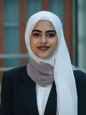 Tayebah smiling with the interior of the Ross building in the background.