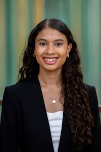 Photo of Marlien William Michigan Ross BBA student wearing a black suit jacket and a white shirt. She has long dark curly hair and is smiling. 