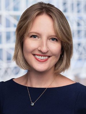 A woman smiling with short blonde hair and a dark navy shirt