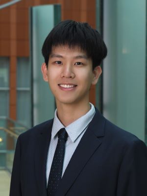 Andrew wears a suit and tie, smiling in the Ross Winter Garden