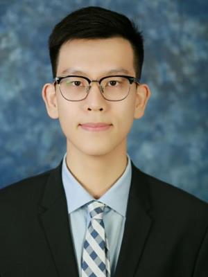 Andrew (Chun Ngai) Chie poses in a black suit in front of a blue background