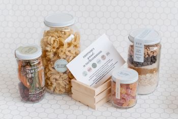 Jars of groceries on a white tile background