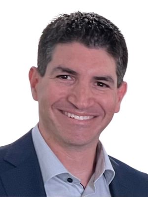 Evan smiles, wearing a blue blazer in front of a white background