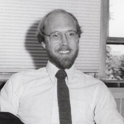 Black and white photo of a professor in a white dress shirt and tie