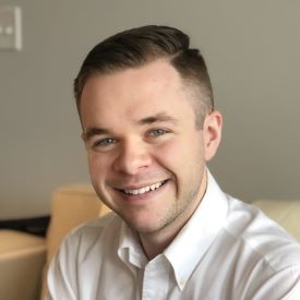 Jack smiles , wearing a white shirt in front of a beige beackgrount