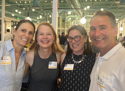 A group of four alums pose together for a group selfie