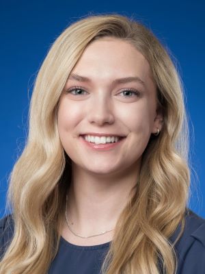 Mia smiles in front of a blue background