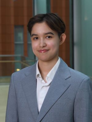 Panathip smiles, wearing a gray suit and standing in the Ross Winter Garden