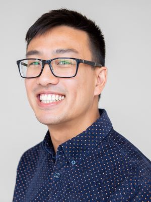 A headshot photo of Patrick with a gray background.