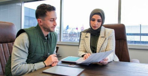 Mariam working at a desk with another person, reviewing documents