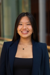 Woman with long dark hair smiling and wearing a dark suit