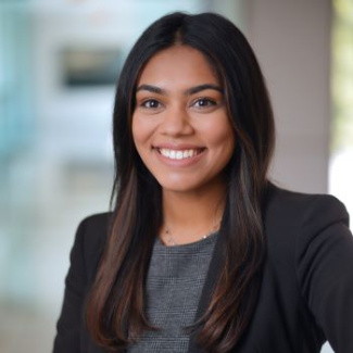 Photo of a woman with long dark hair wearing a black suit and smiling