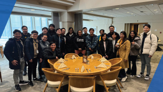 The students in the GMBA Class of 2025 gathered around a table for a group photo