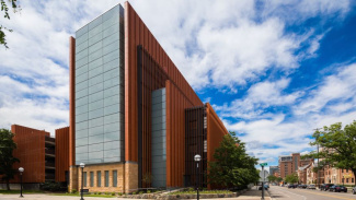 Photo of the Ross School of Business building on a bright sunny day with clouds in the sky. 