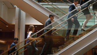 Full-time students walk up the stairs in the Ross building