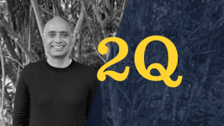 A black and white photo of Shah standing in front of some trees displayed alongside the 20Qs logo