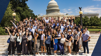 A large crowd of MAcc students pose for a group photo in front of the White House in the capitol.