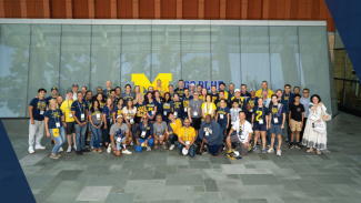 A large crowd of alumni standing in front of the Ross School of Business for a group photo