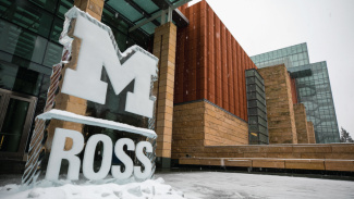 An ice sculpture of the Michigan Ross logo standing in front of the building in the snow