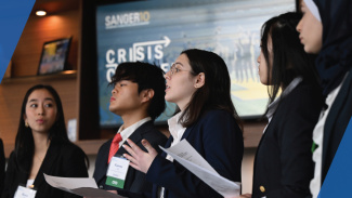 A group of five students presenting a crisis response plan on stage