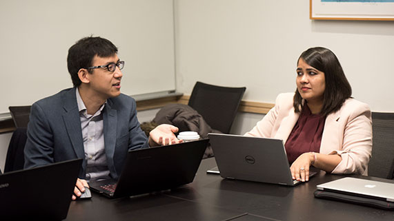 two students working on laptops