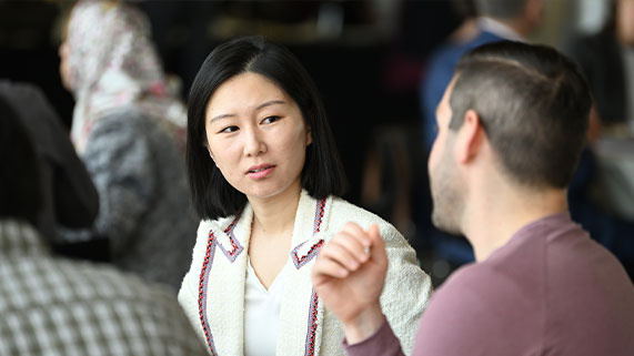 PhD student sitting at a table talking to other students