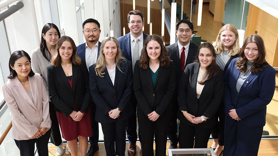 group of 11 students standing on staircase in business attire 