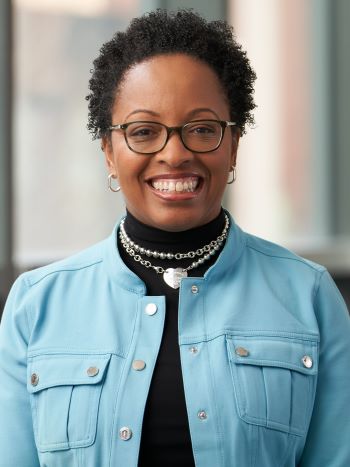 Tiffanie Boyd standing in front of a background with windows, smiling.